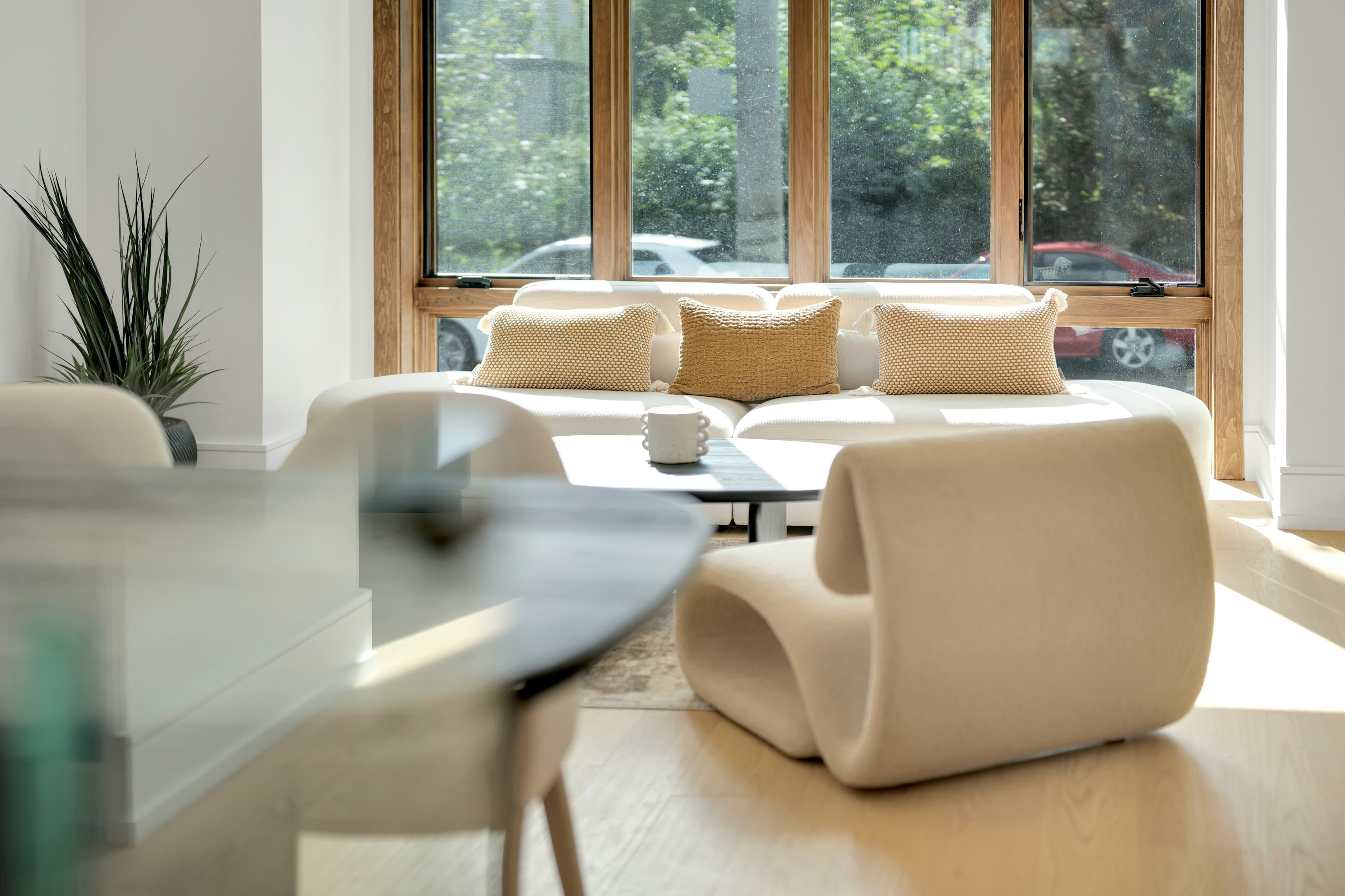 Contemporary living room with a large wood-framed window, light flooring and seating — property canvas for Archava observations